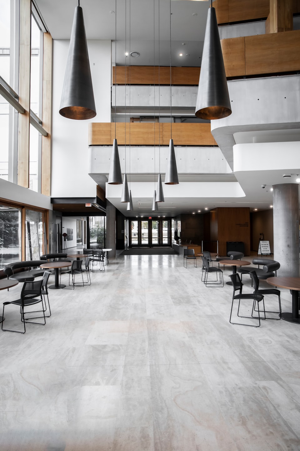 Modern lobby with round tables, black chairs, and tall windows.