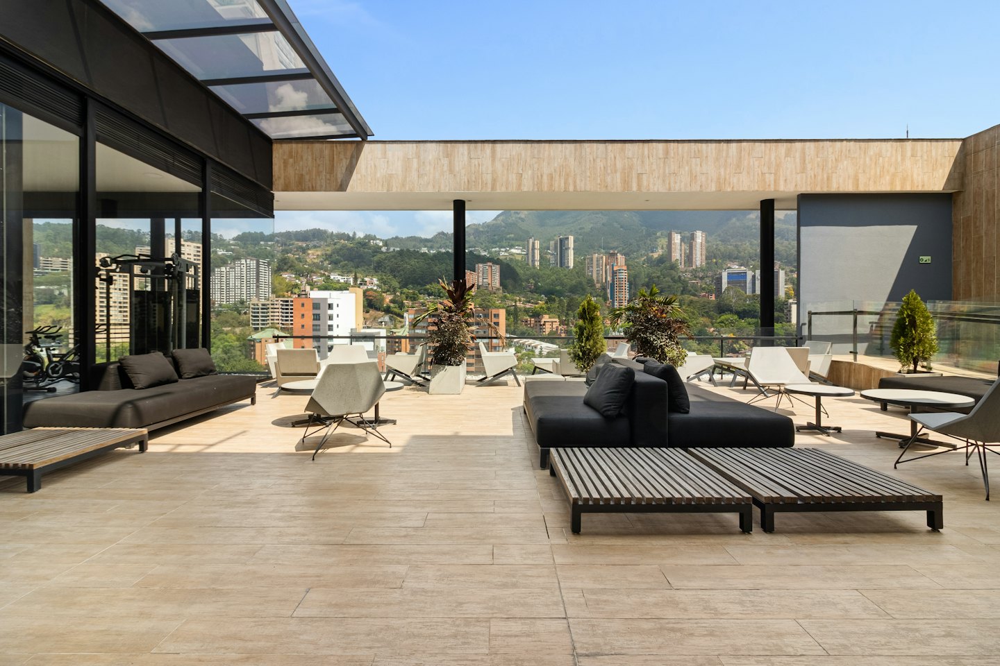 Modern rooftop terrace with lounge seating overlooking a sprawling city.