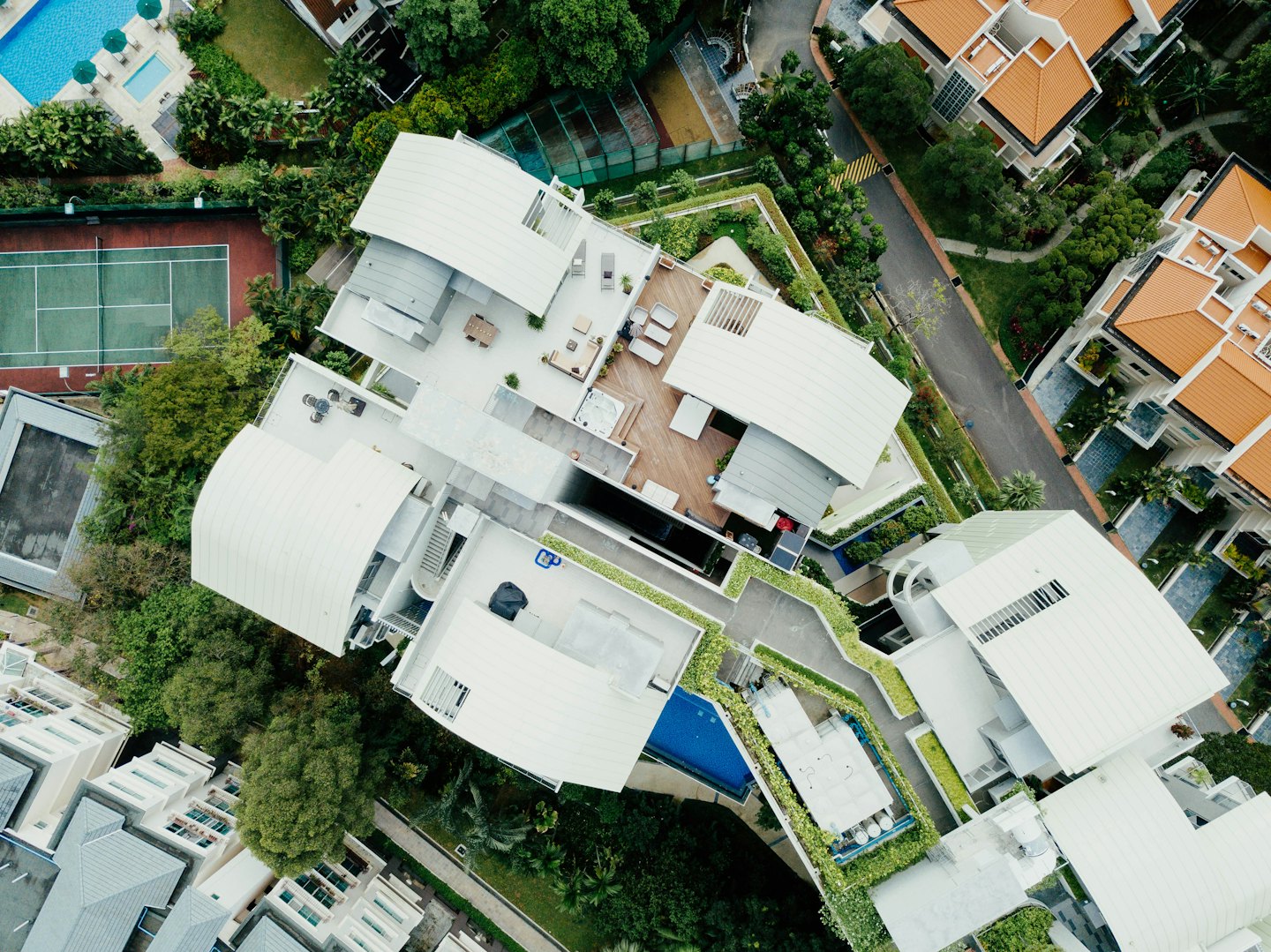 Aerial view of a modern residential complex with pools and landscaping.