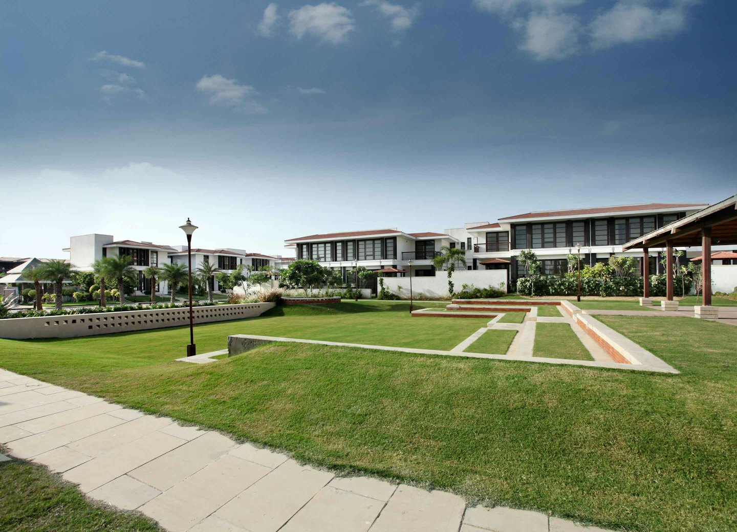 Modern white apartment buildings with brown roofs and green lawns.