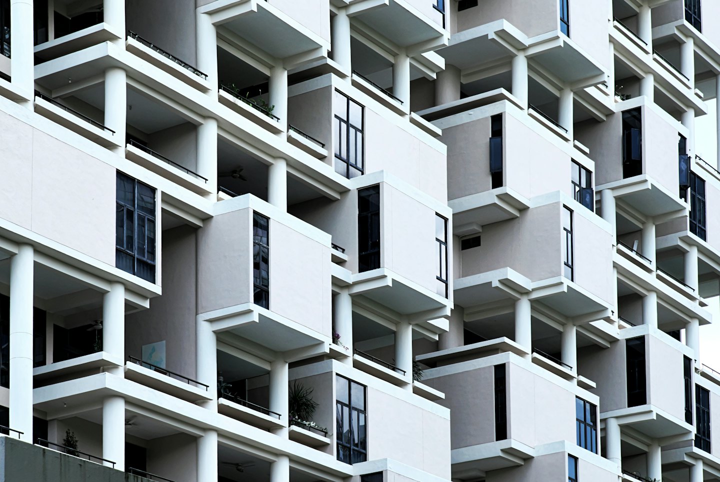 Modern multi-story apartment building with geometric balconies and greenery.