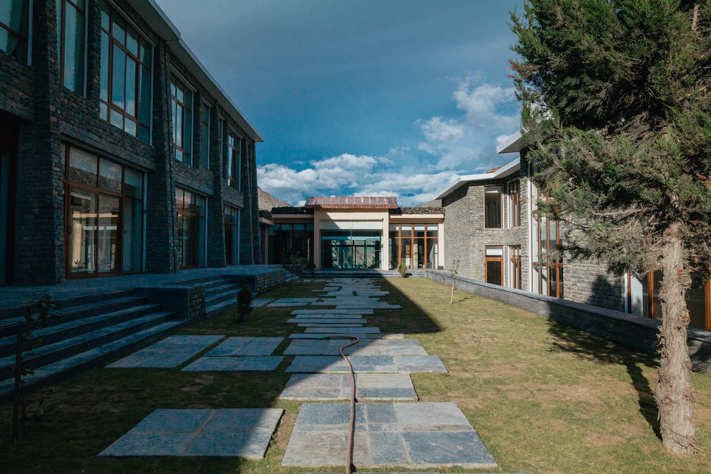 Modern complex with grey stone buildings and a green courtyard.